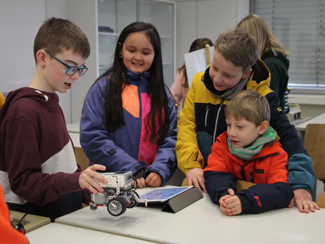 Schüler erklärt Gästen einen Lego-Roboter