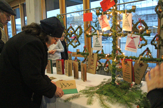 Frau schaut sich an einem Stand eine selbst gebastelte Weihnachtskarte an