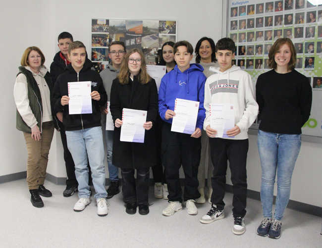 Gruppenfoto mit Schulleiterin, Mathelehrerinnen und Siegern des Mathewettbewerbs mit Urkunden in der Hand