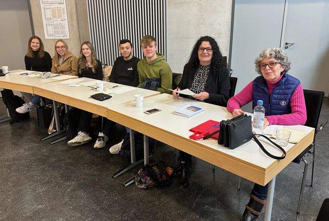Schüler und zwei Frauen an einem langen Tisch