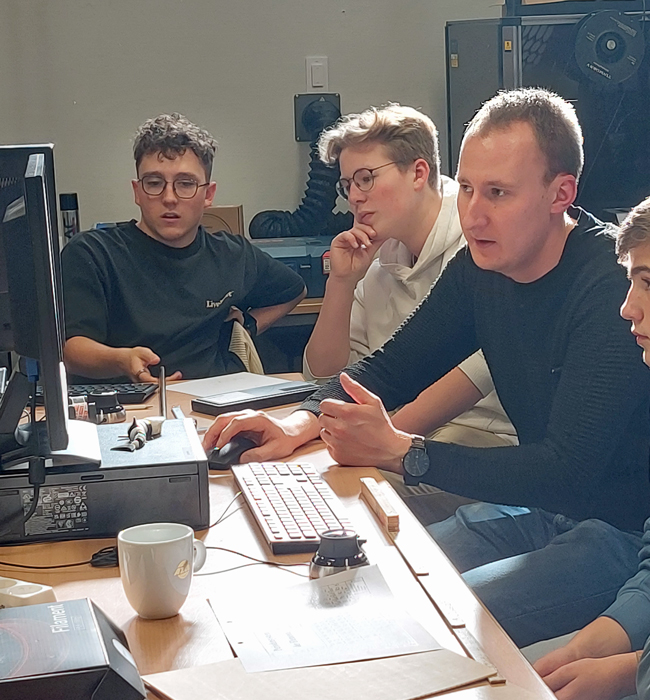 Lehrer und Schüler vor PCs schauen angestrengt und gespannt