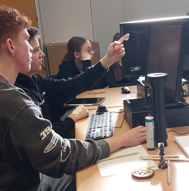 Zwei Schüler vor einem PC unterhalten sich