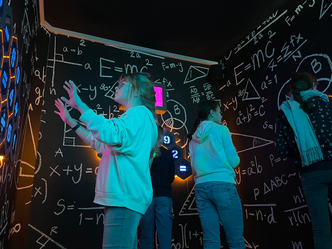 Schüler in einem Raum voller mathematischer Zeichen an den Wänden
