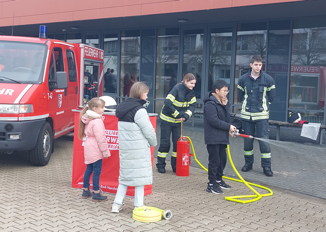 Schüler in Feuerwehruniform vorm Feuerwehrauto