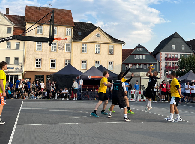 Erwachsene, die gegeneinander Basketball spielen, fast wolkenfreier Himmel