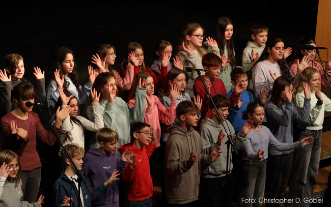 Chorschüler singen und machen Handbewegungen
