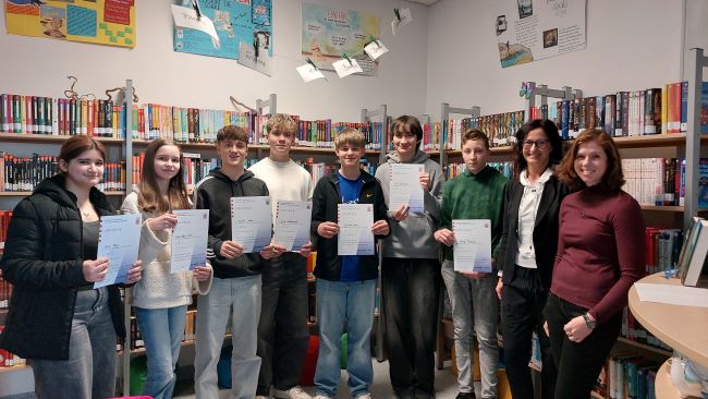 Schülergruppe mit Urkunden in der Bibliothek