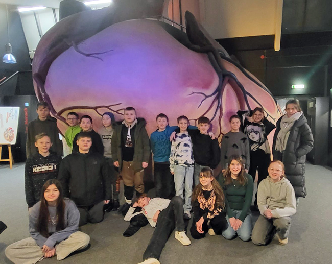 Schülergruppenbild vor einem überdimensionalen Herzmodell