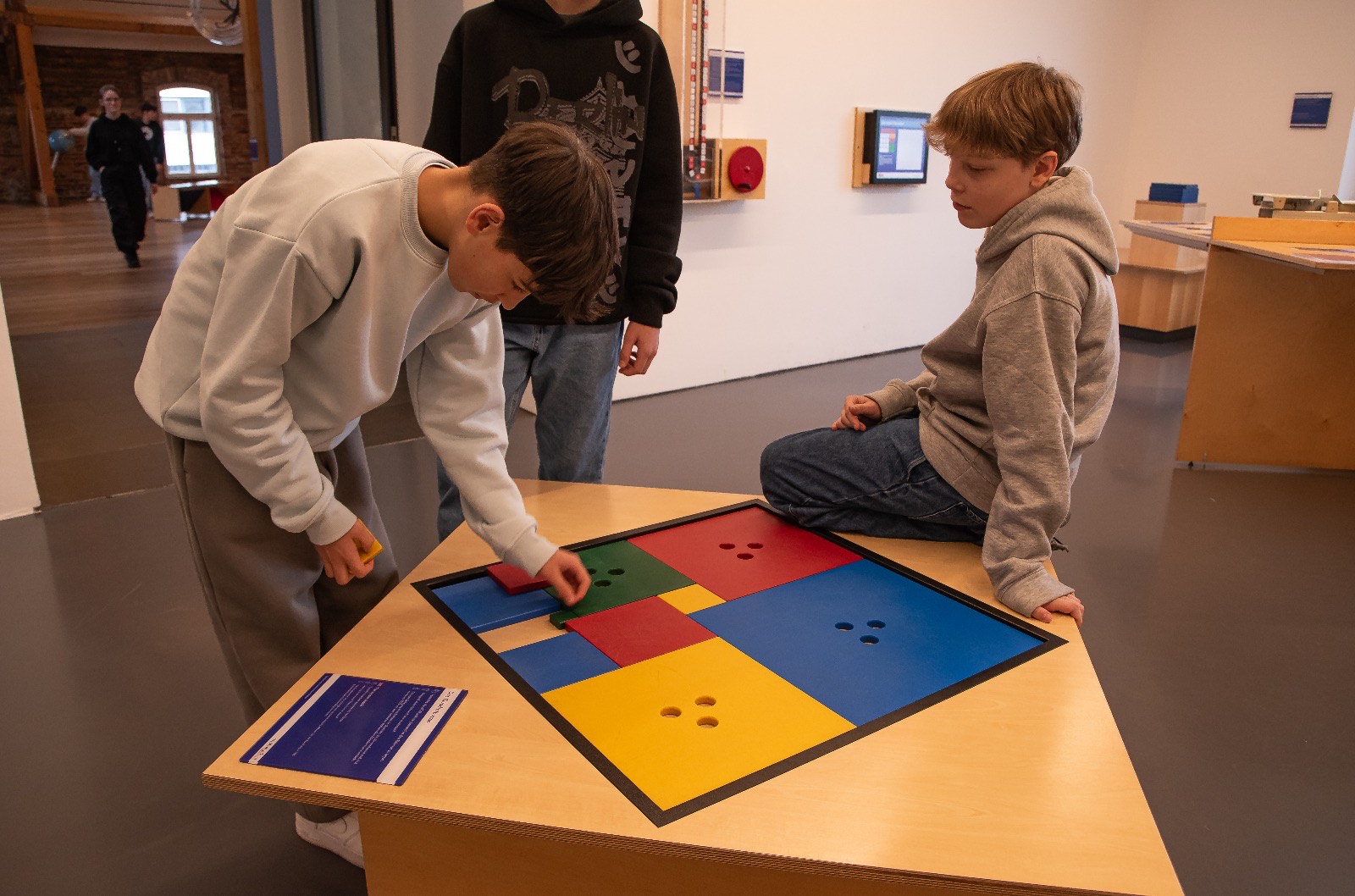 Zwei Schüler an einem Tisch mit bunten Vierecken, an denen sie etwas machen
