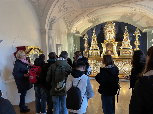 Schüler vor goldenen Statuen im Dom, Museumsführerin erklärt ihnen etwas