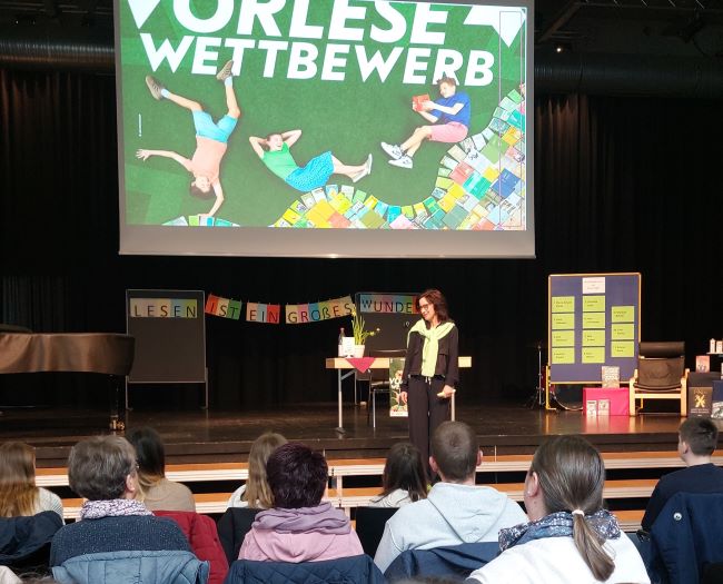 Schulleiterin begrüßt Teilnehmer und Publikum