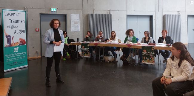 Die Jurymitglieder sitzen an einer Tischreihe neben dem Publikum vor der Bühne
