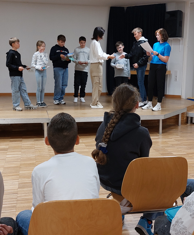 Schüler stehen mit Lehrern auf der Bühne und erhalten Preise