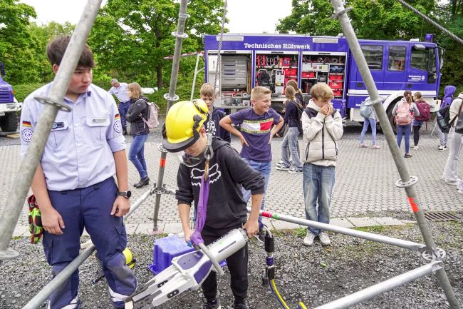 Schüler am Stand des THW mit Fahrzeug im Hintergrund