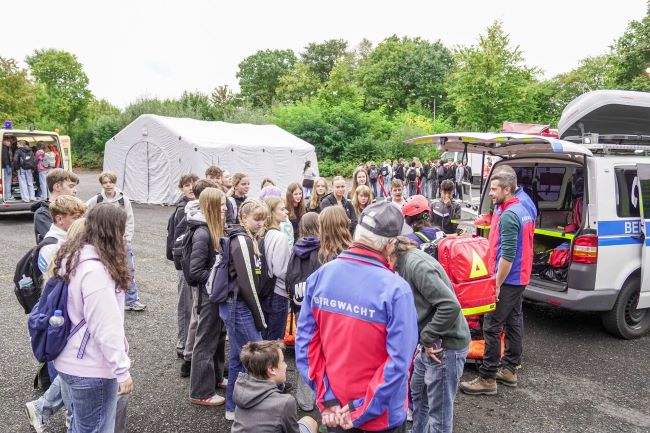 Schüler auf einem großen Platz, auf dem ein Rettungszelt aufgebaut ist und verschiedene Rettungswagen stehen