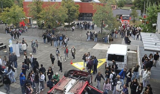 Blick auf den Schulhof mit vielen Schülern und Autos von Ausstellern