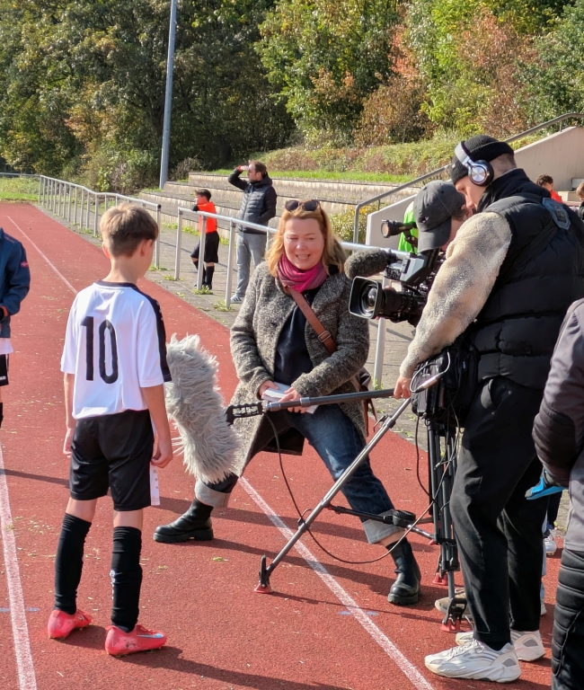 Junge vor einem Fernsehteam am Spielfeldrand stehend wird interviewt