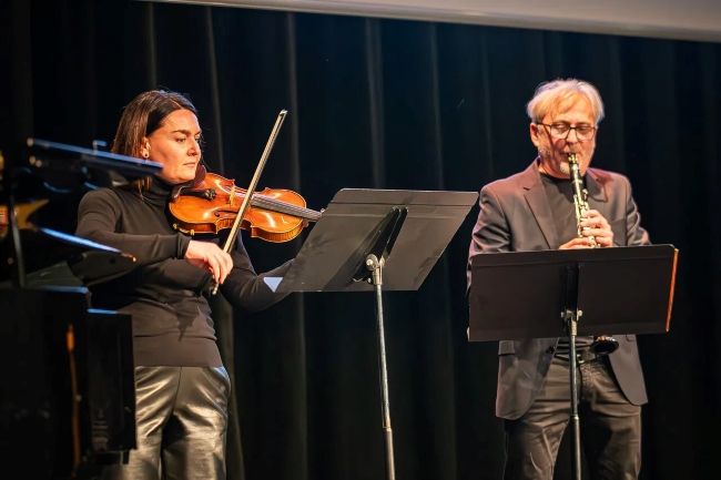 Geigenspielerin und Klarinettenspieler auf der Bühne spielend hinter Notenständern stehend