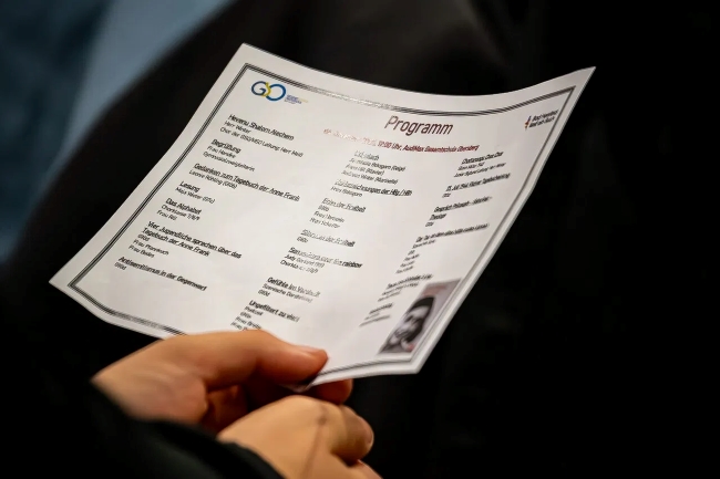 Hände, die einen Ablaufplan der Veranstaltung halten, auf dem viele Punkte stehen