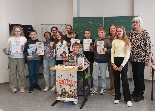Gruppenbild aller Teilnehmer und der Jury vor der Tafel in einem Klassenraum