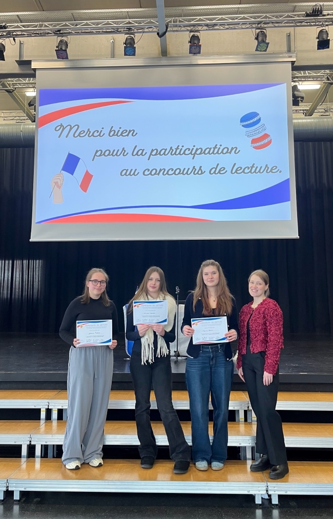 Lehrerin mit drei Schülerinnen auf der Bühnentreppe mit Urkunden