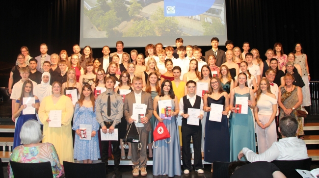 Gruppenbild - Lehrer und viele Schüler mit Urkunden auf der Bühne