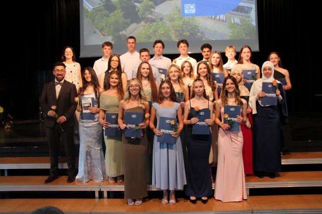 Gruppenfoto einer Schülergruppe mit Zeugnissen und Klassenlehrer
