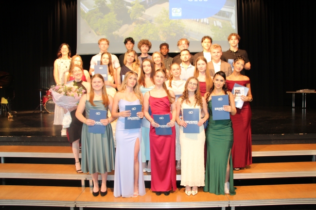 Gruppenfoto einer Schülergruppe mit Zeugnissen und Klassenlehrer
