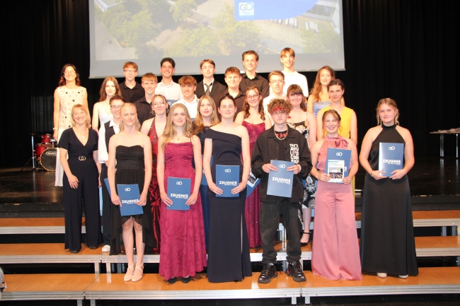 Gruppenfoto einer Schülergruppe mit Zeugnissen und Klassenlehrer