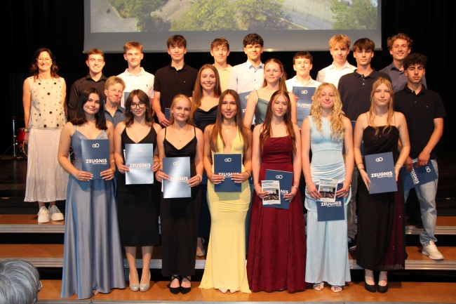 Gruppenfoto einer Schülergruppe mit Zeugnissen und Klassenlehrer
