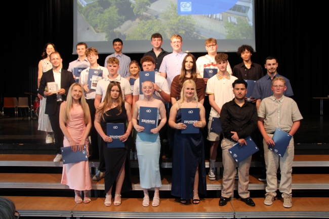 Gruppenfoto einer Schülergruppe mit Zeugnissen und Klassenlehrer