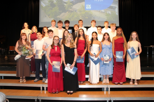 Gruppenfoto einer Schülergruppe mit Zeugnissen und Klassenlehrer
