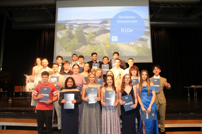 Gruppenfoto einer Schülergruppe mit Zeugnissen und Klassenlehrer