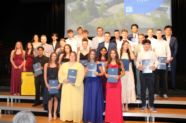 Gruppenfoto einer Schülergruppe mit Zeugnissen und Klassenlehrer
