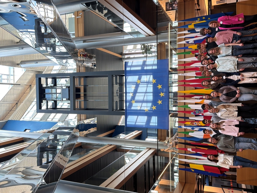 Schüler in einem riesigen Gebäudeflur mit Europaflagge und den dazugehörigen Landesflaggen und Blick auf einen hohen Fahrstuhl