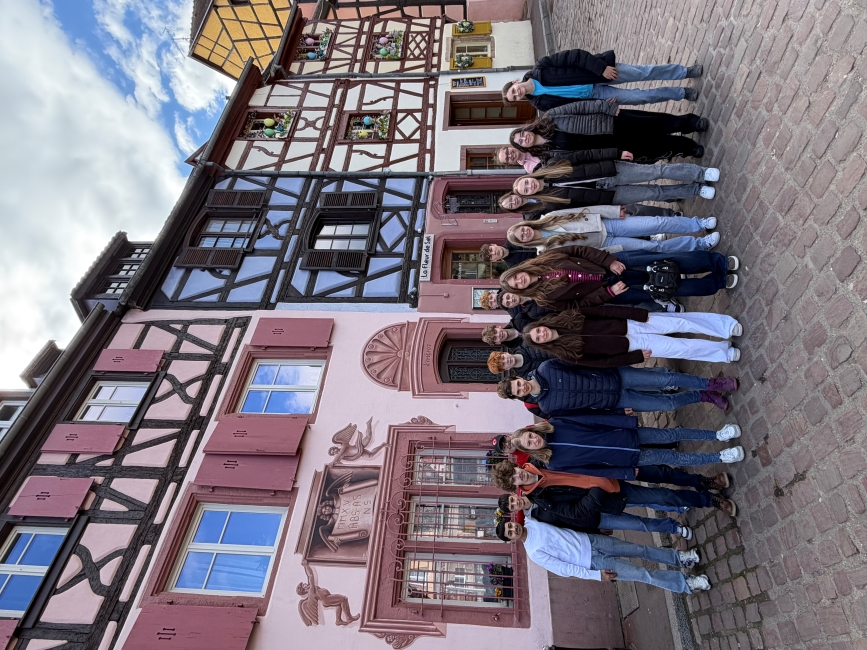 Gruppenbild vor bunt bemalten Fachwerkhäusern, die hinter den Schülern eng aneinandergereiht stehen