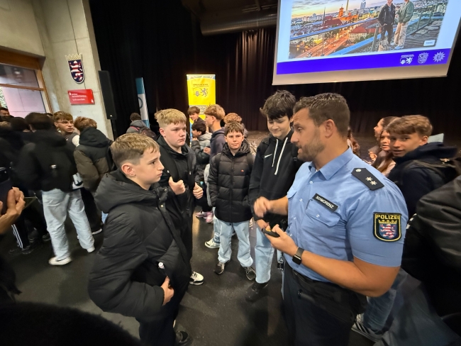 Nahaufnahme von einem Gespräch zwischen Schülern und dem Polizisten nach der Veranstaltung vor der Bühne