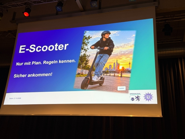 Präsentationsfolie mit Titel der Veranstaltung und Bild eines E-Roller-Fahrers auf einer großen Leinwand